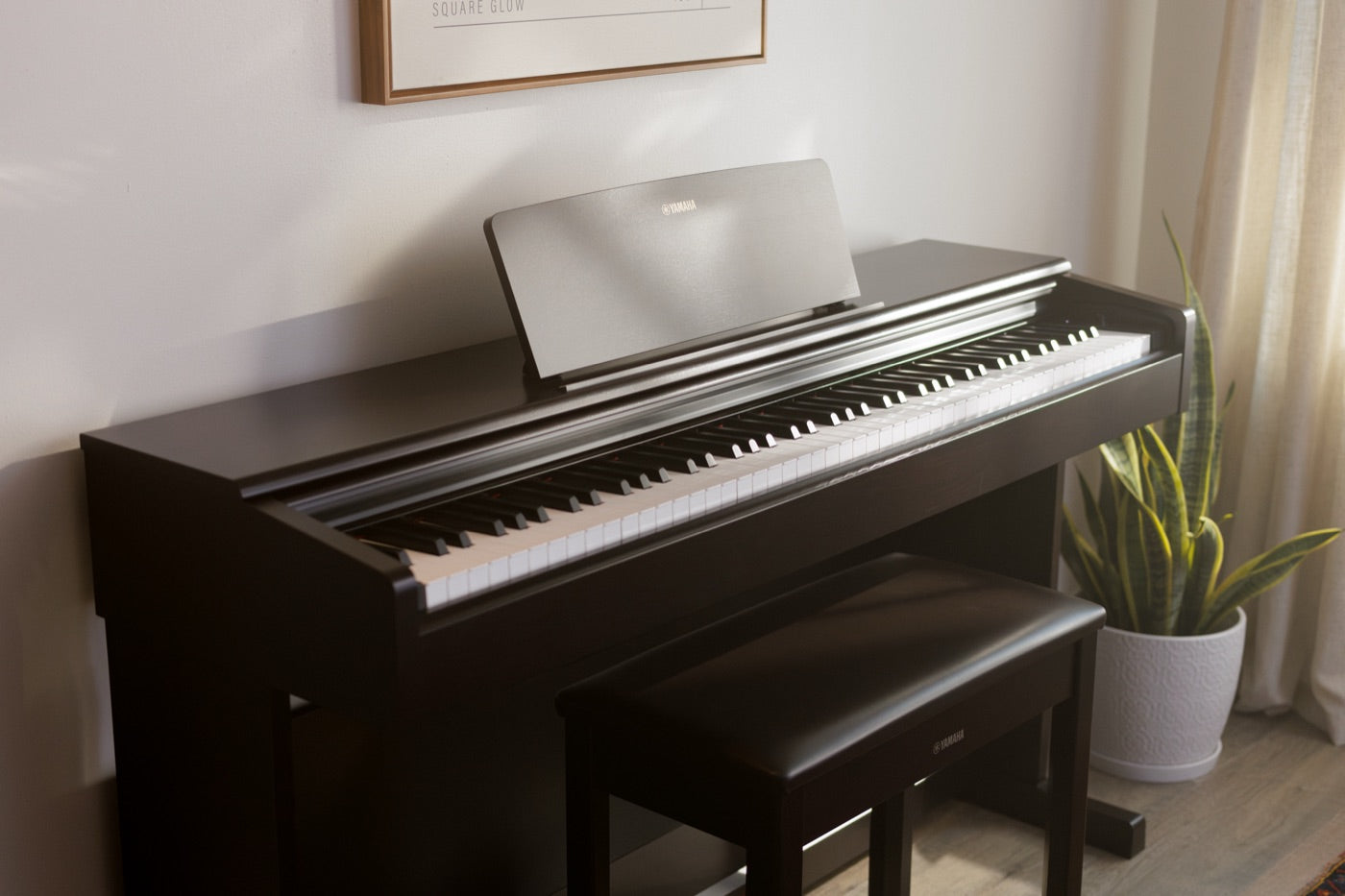 Yamaha Arius upright digital piano with matching bench in a styled living room