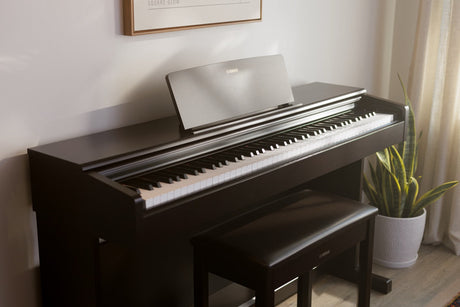 Yamaha Arius upright digital piano with matching bench in a styled living room