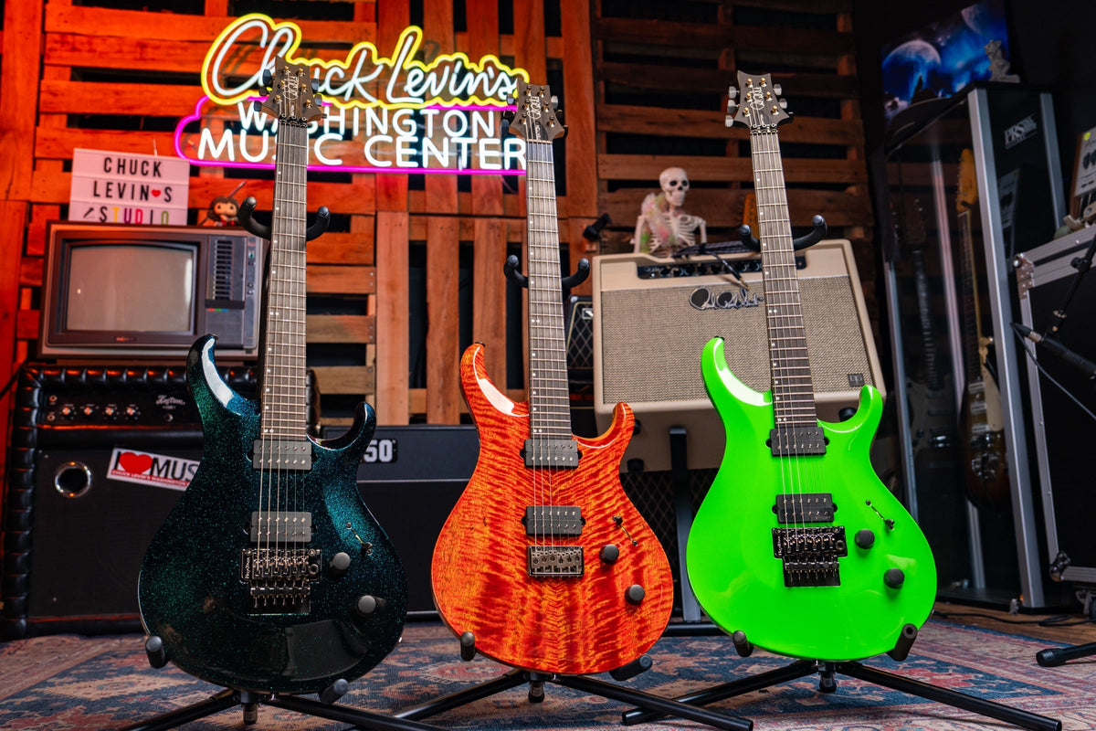 Three PRS Tekton guitars on stands at Chuck Levin’s